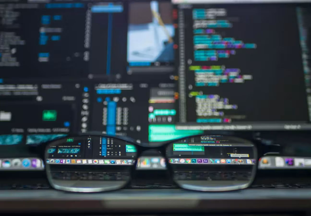 Bildschirme Monitore mit Code und einer Brille auf dem Tisch